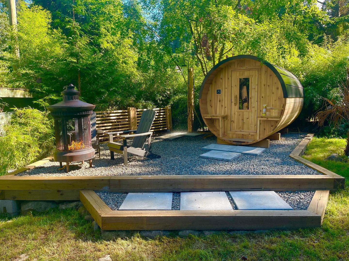 A barrel sauna and fire pit surrounded by forest at Boho House